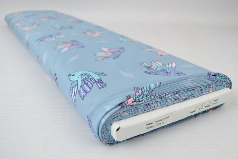 LYSEBLÅT VISKOSE STOF MED PASTEL FUGLE PRINT – LET FALD & ELEGANT MAT GLANS